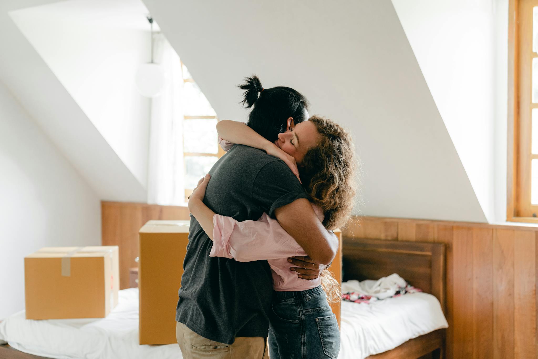 first time home buyers hugging in their new home, surrounded by boxes, symbolizing a fresh start.