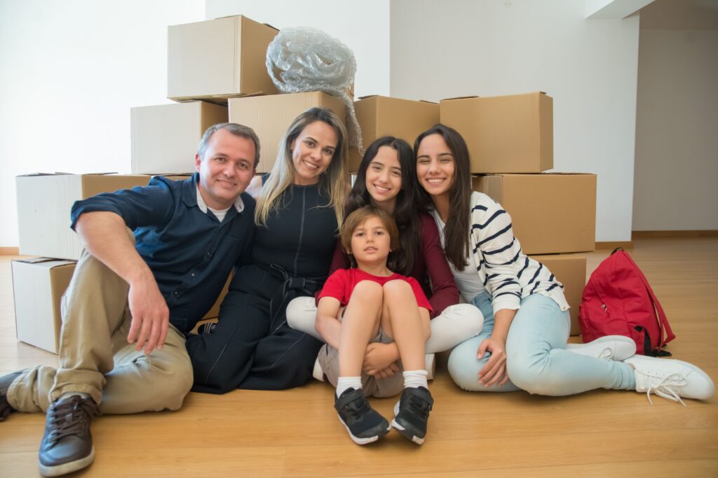 Growing family sitting together with moving boxes in their move up home.